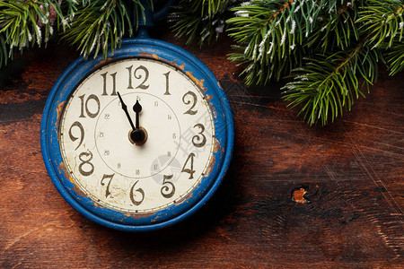 圣诞贺卡与闹钟和枞树枝在木纹理背景圣诞背景带有复制空间的顶视图片