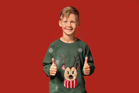 穿着圣诞毛衣的可爱男孩在彩色背图片