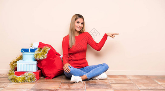 圣诞节假期女孩坐在地板上指着手指图片