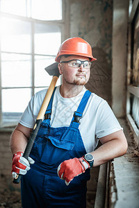 一名疲劳工人站在建筑工地的窗户附近图片