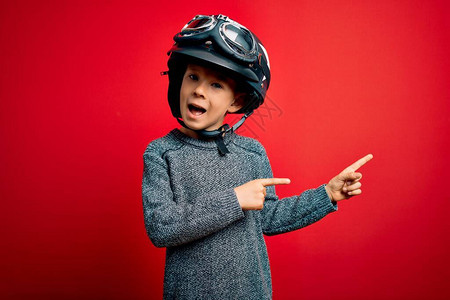 年轻caucasiansian小男孩身着老式摩托车头盔和红背景的谷歌图片