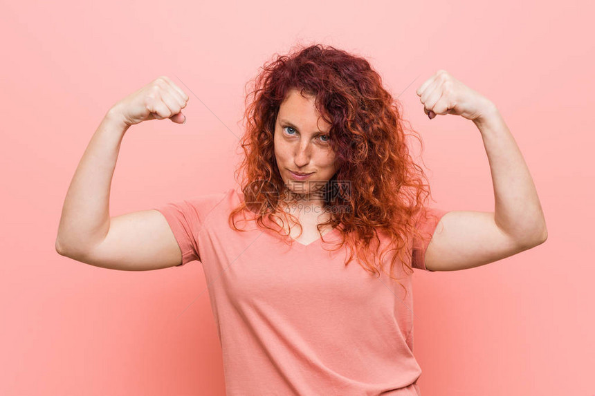 年轻自然而真实的红发女用手臂展示力量姿态图片