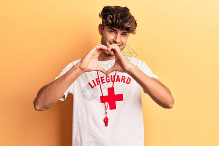 穿着救生衣T恤的西班牙年轻人在爱情中笑着吹口哨用双手做心脏符号形状图片