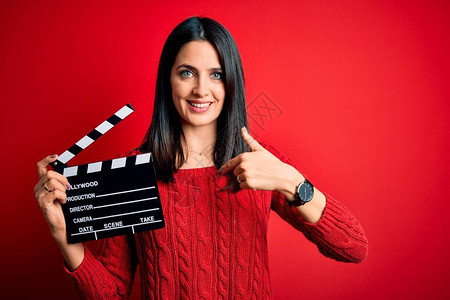 蓝眼睛的年轻女导演拍电影时把掌盘放在红色背景上满脸惊喜的脸面向自己指图片