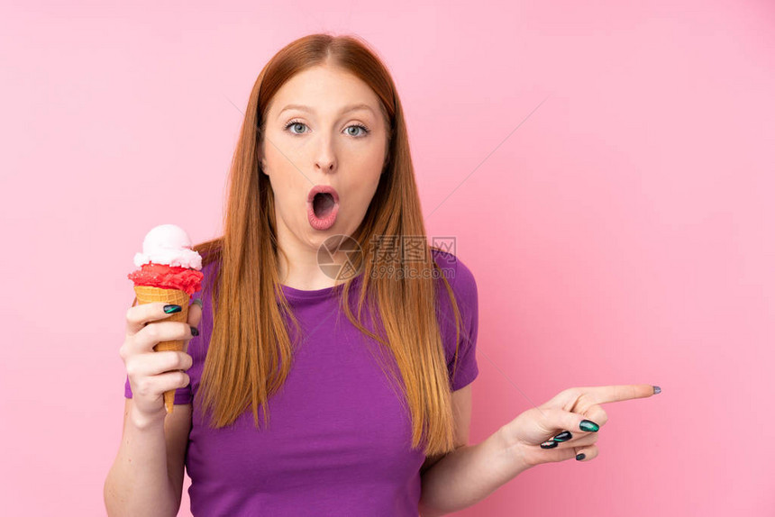 年轻红发女红发小姑娘带着玉米角冰淇淋在孤立的图片