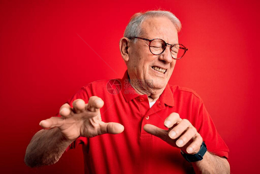 灰色头发的老年男子穿着眼镜和散发T恤穿红色背景令人厌恶的表情图片