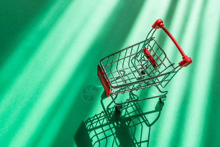 绿色背景的超市购物车的小副本购物杂货店购物折扣促销的概念极简主义图片