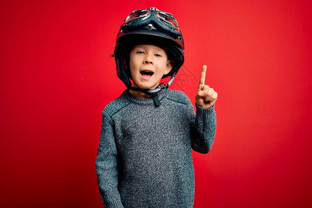 年轻的caucasian小孩穿着老式摩托车头盔和红背景的谷歌图片