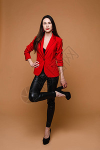 身穿红色夹克黑色皮裤和黑色鞋子的长着深色直发的年图片