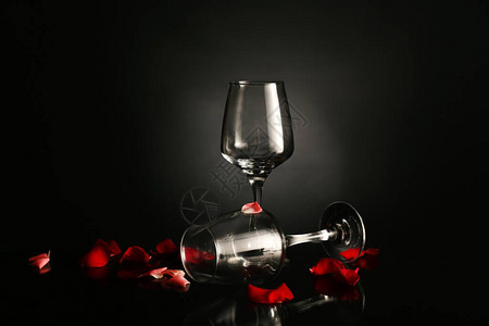 深色背景中带玫瑰花瓣的酒杯图片