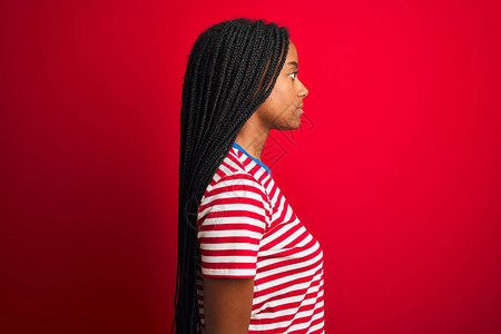 身穿条纹T恤的年轻美国女站在孤立的红色背景上图片