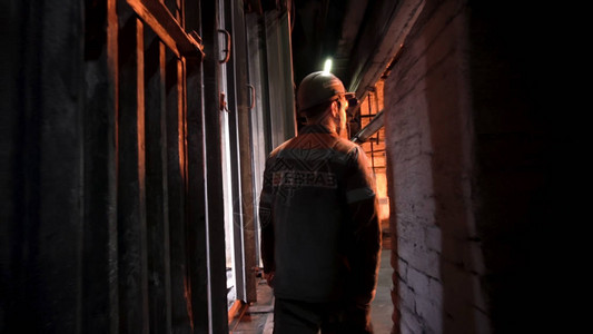 铸造工人穿着制服穿过冶金厂走廊的后视图图片