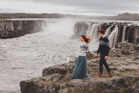 快乐的时髦情侣在冰岛受欢迎的塞尔福斯瀑布附近散步背景图片