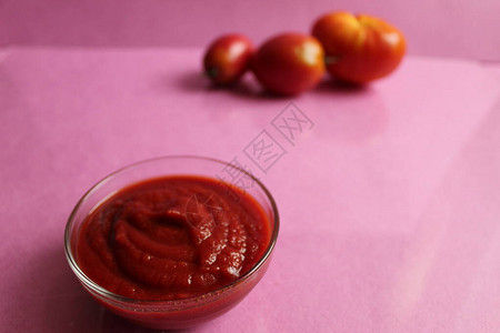 旁边一个玻璃酱盘的红番茄酱盘里有蔬菜西红柿和洋葱在粉红色背图片