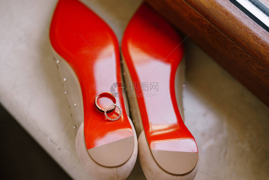在芭蕾舞鞋红底丝上为窗台上的新娘织金环图片