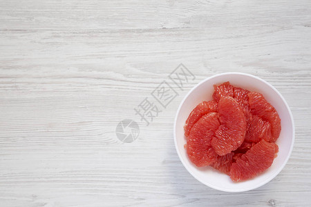红葡萄柚片放在白色木制背景的白色碗里图片