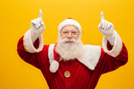 圣诞老人在黄色背景上拿一大袋礼物带复制空间出背景图片
