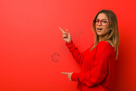 年轻有魅力的真人女人站在一堵墙上兴奋地指背景图片