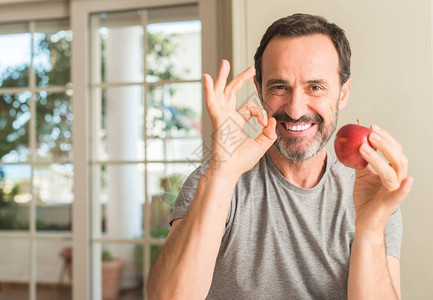 中年男子吃健康的红苹果用手指做好标记图片