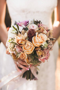 新娘手里拿着橙色秋的小婚礼花束粉红色和橙色的玫瑰白牡丹图片