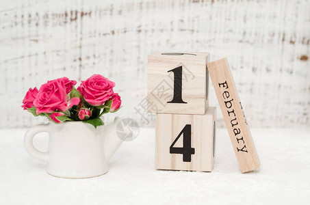 一束红玫瑰和2月14日数据在白色背景上的木制日历上情人节快乐图片