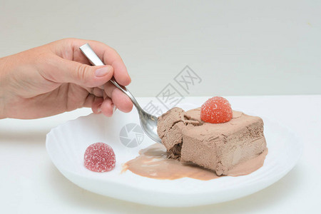 白色盘子上有咖啡冰淇淋和两种果酱在女手中一茶匙一个女人在吃冰淇淋图片