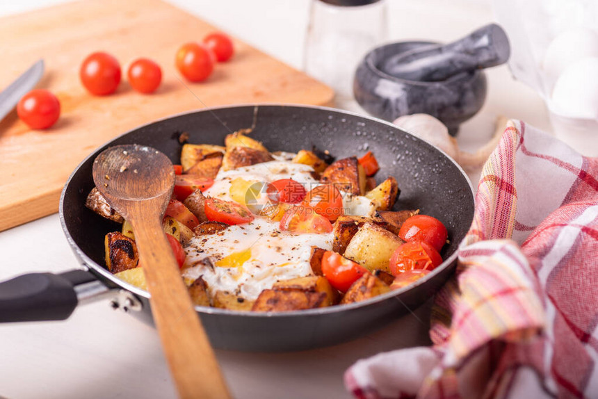 男人的生锈早餐炸土豆和鸡蛋樱桃番茄在锅里图片
