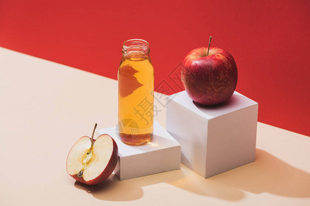 红底苹果和白色立方体附近的瓶图片