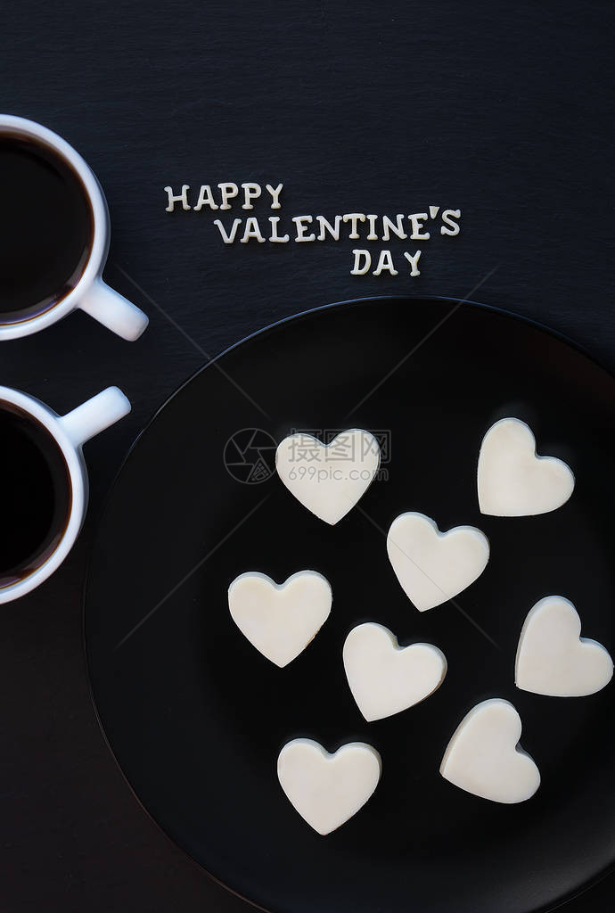 两杯咖啡和巧克力糖果白色的心形刻着快乐的图片