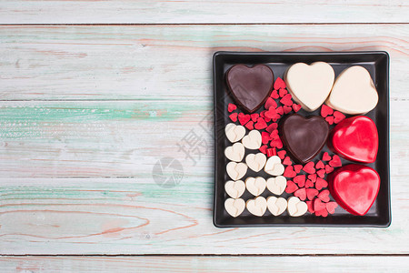 红棕色白不同大小的心形自制甜巧克力五彩纸屑布置在甜点黑盒中图片