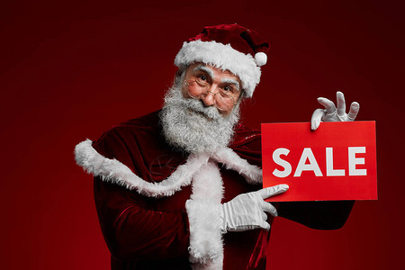微笑的圣诞老人的腰部肖像举着销售标志图片