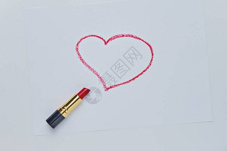 红色的心在白色的红色唇膏绘制白色背景上的素描特写情人节浪漫背景图片