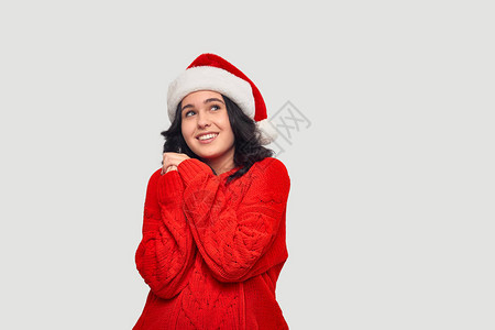 穿着红色毛衣的美丽的黑发女孩和圣诞老人帽子梦想着圣诞节和新图片