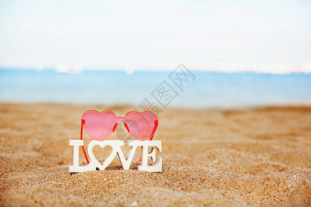 爱和粉红色的心形眼镜在沙滩图片