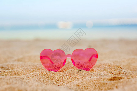 沙滩上的粉红太阳镜有蓝海背景蜜月度图片