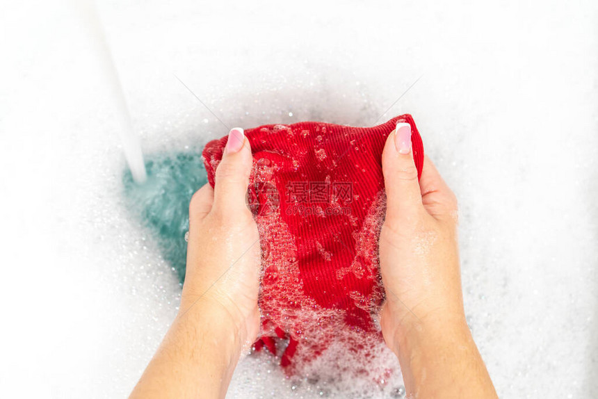 洗鲜红色衬衫的女手图片