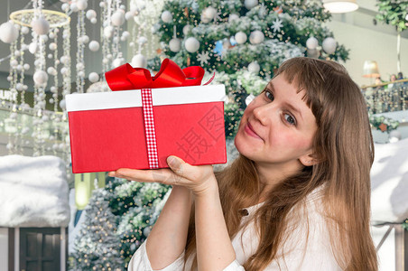 美丽的微笑的女人与红色礼物盒在圣诞图片