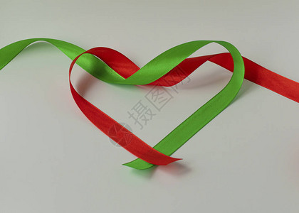 用于在白色背景上装饰礼物的缎带卷红色和绿色的丝绸和缎带呈心形图片