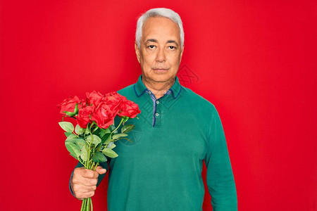 中年灰发男子手拿浪漫的红玫瑰花束图片
