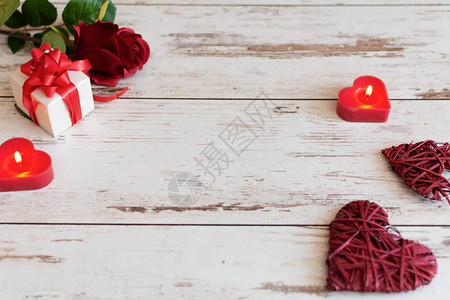 红玫瑰与心和木制背景上的蜡烛圣情人节或婚礼卡概念与文图片