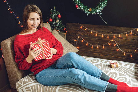 一位穿着红色毛衣的快乐年轻女子坐在沙发上图片