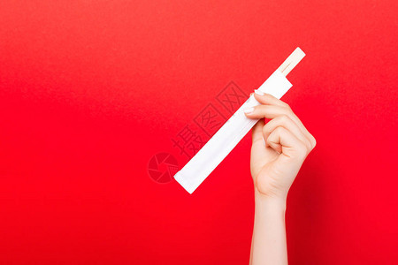 女人手握着红背景的筷子图片