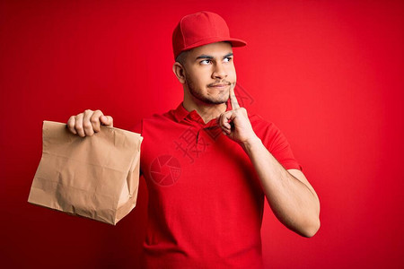 年轻英俊的送货员拿着纸袋和外卖食品图片