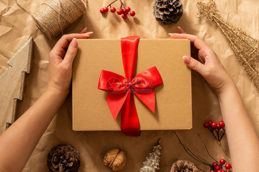 女手拿着工艺纸背景上的礼品盒带有圣诞气氛的冬季节日作文图片