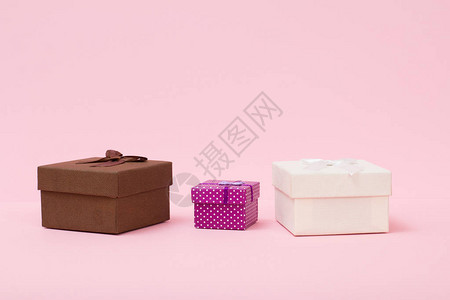 粉红色背景上不同大小和颜色的礼物盒庆祝日的概图片