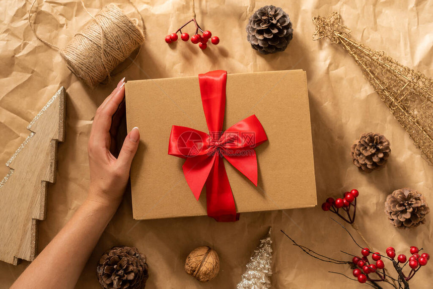 女手拿着工艺纸上的礼品盒带有圣诞气氛的冬季节日作文图片