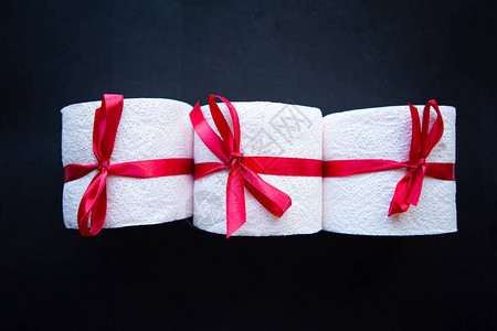 卫生纸卷包裹在黑色背景上的礼品蝴蝶结中Covi图片