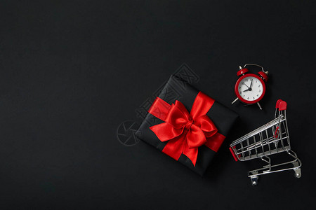 黑色背景中的礼品盒闹钟和购物车图片