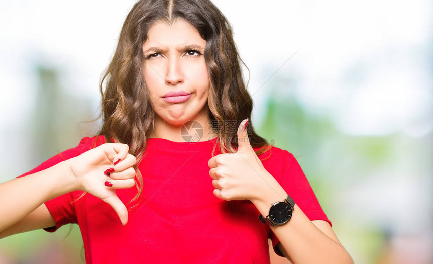 年轻美女穿着临时T恤穿轻便的T恤在上下伸起拇指不同意见和图片
