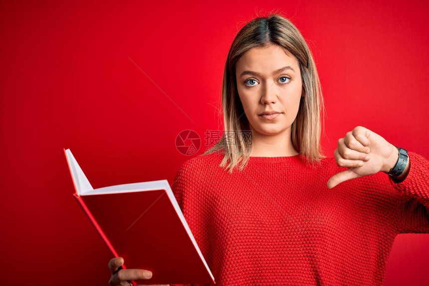 年轻美女看书站在孤立的红色背景上满脸愤怒的脸图片